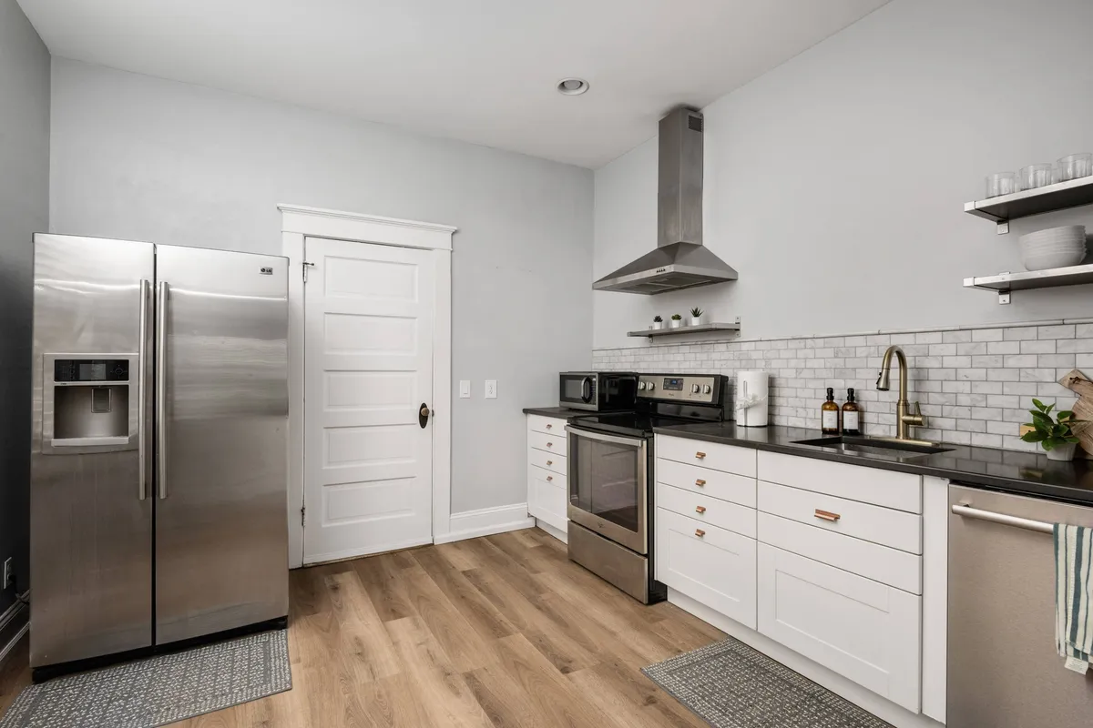 A spacious, modern kitchen with stainless steel appliances, crisp white cabinetry, and warm wooden flooring. The layout is open and inviting, ideal for meal prep or casual gatherings, with a sense of contemporary comfort.