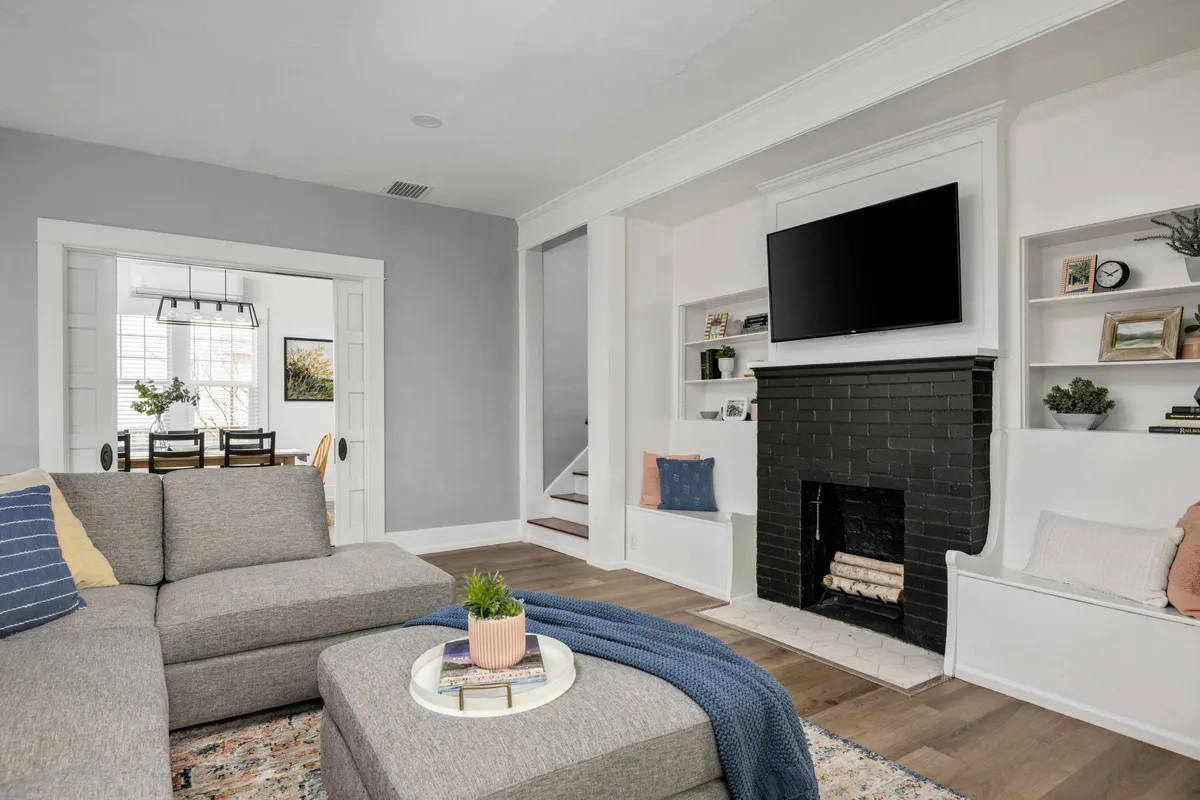 A cozy interior scene featuring a comfortable sofa set near a fireplace and an adjoining dining area. The space is designed for relaxation and togetherness, perfect for family gatherings or unwinding after a day. The soft lighting and inviting decor promote a sense of peace and comfort.
